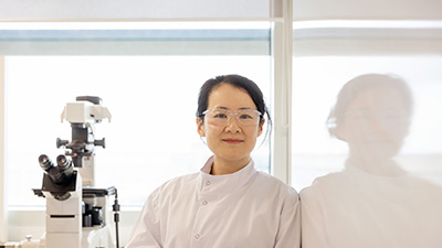 Woman in a labcoat smiling at the camera