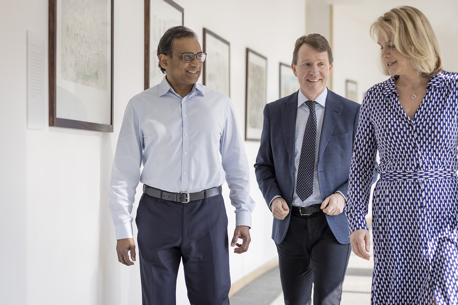 A group of three people walking together in an office hallway