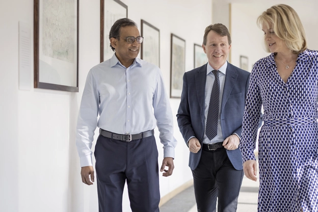 A group of three people walking together in an office hallway