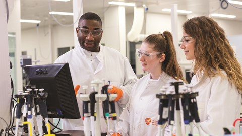 Three scientists in a GSK lab looking at a computer screen