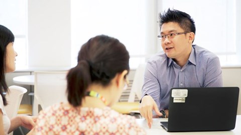 GSK Employees holding a meeting at a table with an open laptop