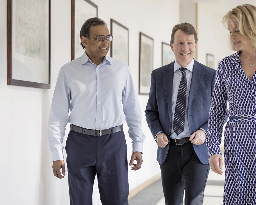 Groupe de trois personnes qui marchent dans un corridor de bureau