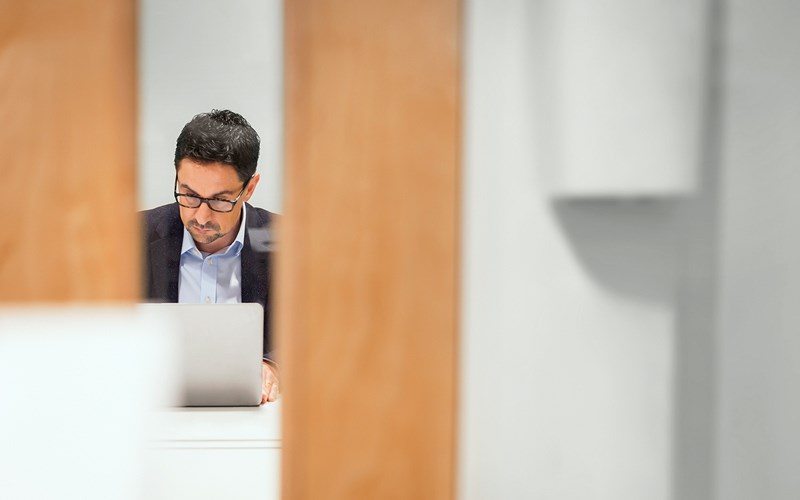 A candid view of a person working on a laptop in an office.