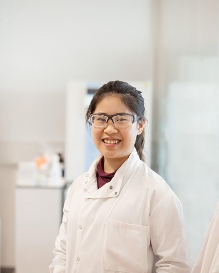 Woman in a labcoat smiling at the camera