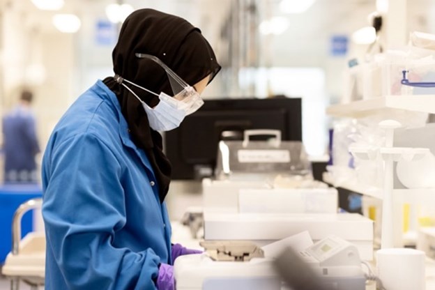 Woman wearing safety glasses looking at a machine