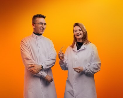 Two people hanging out together in front of an orange background