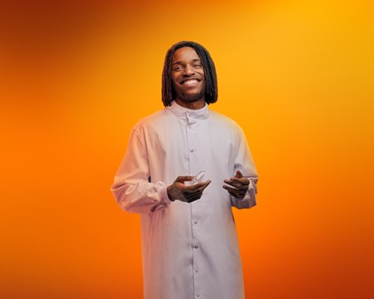 Man holding lab equipment in front of an orange background