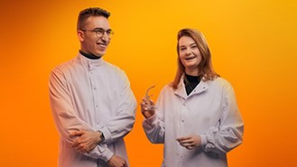 Two people hanging out together in front of an orange background