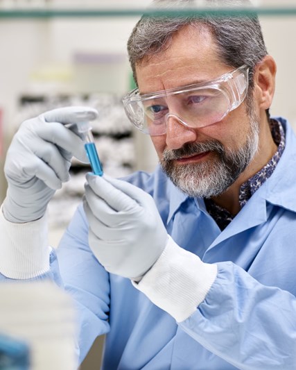 Man in laboratory setting inspecting a blue vial