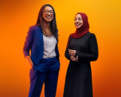 Deux femmes riant ensemble sur fond orange