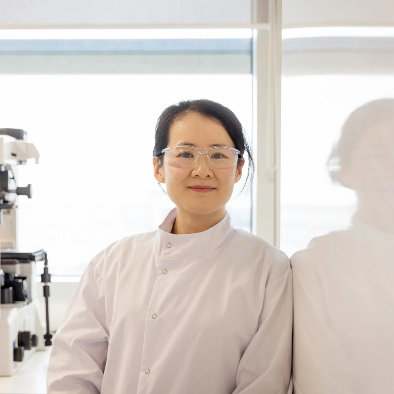 Woman in lab gear in lab looking at camera
