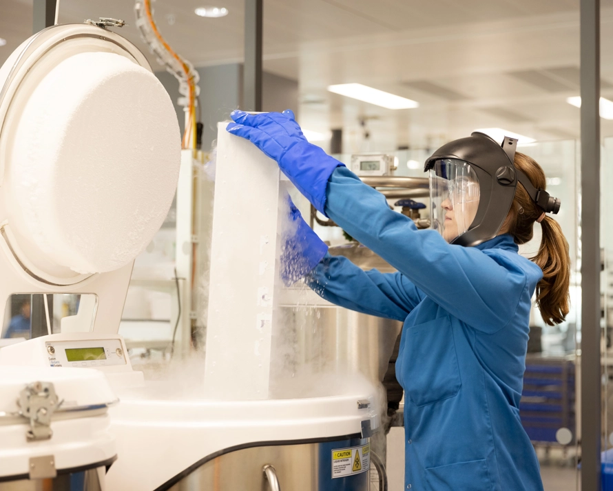 Femme portant un équipement de protection qui ouvre un appareil de laboratoire