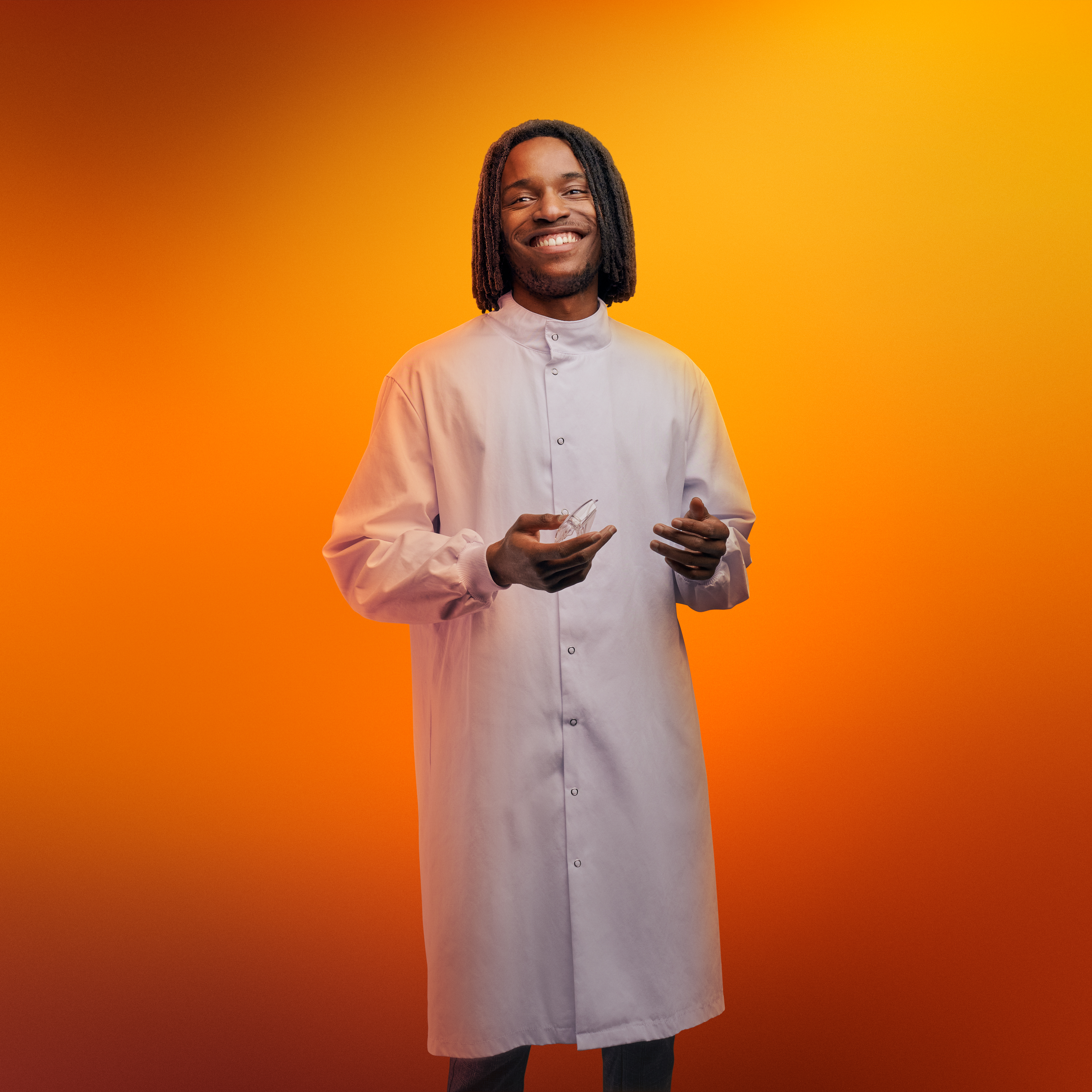 Man holding lab equipment in front of an orange background