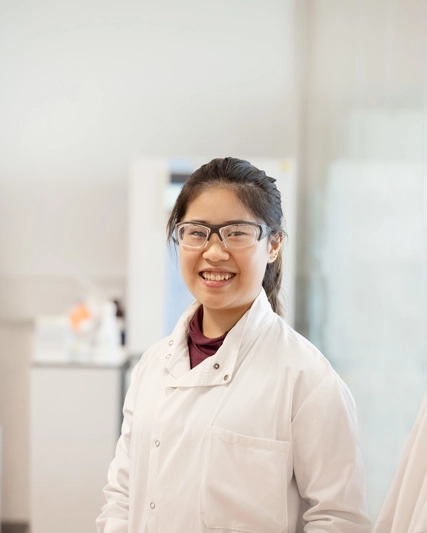 Femme en blouse de laboratoire qui sourit à la caméra