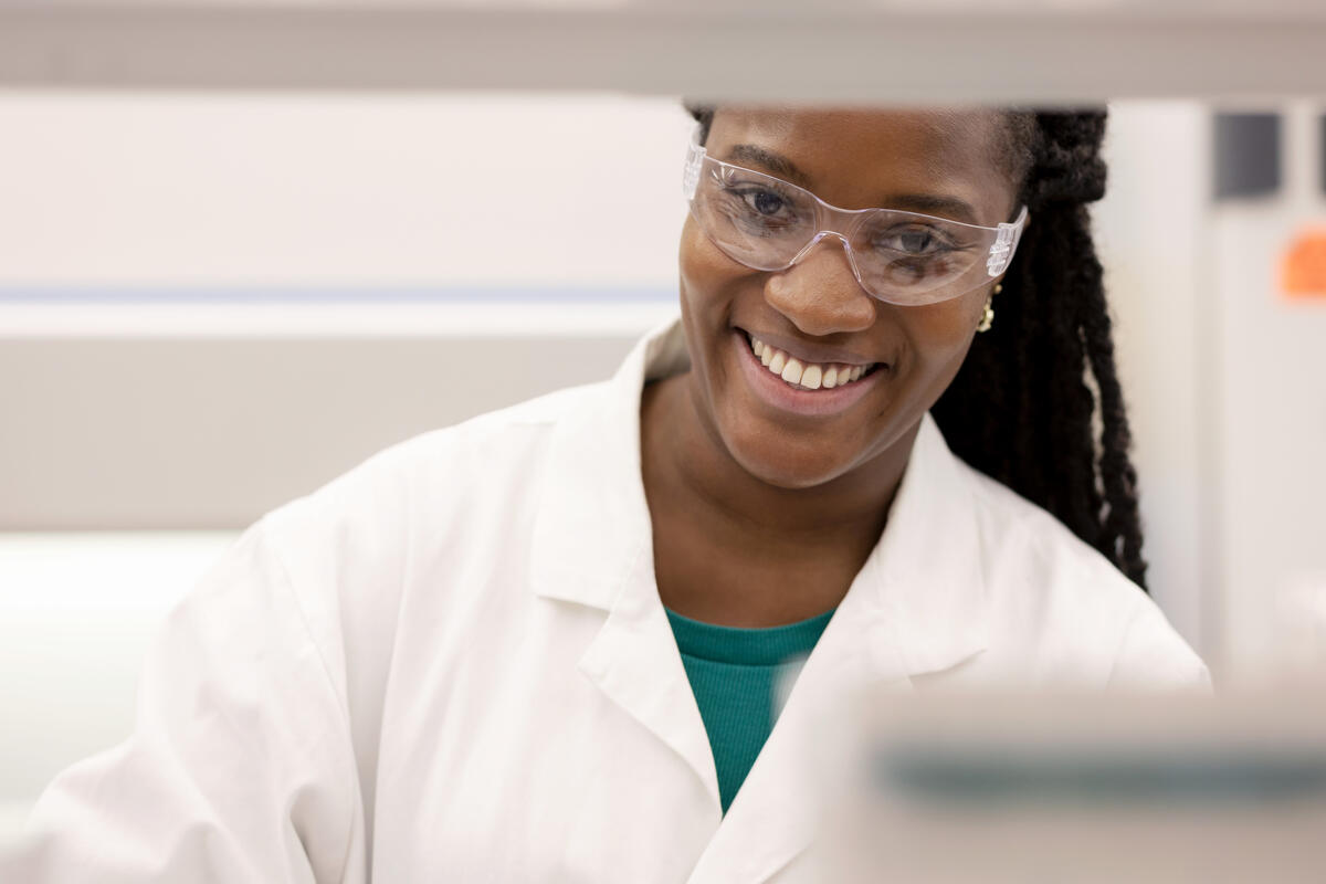 Woman in labratory coat and safety glasses smiling