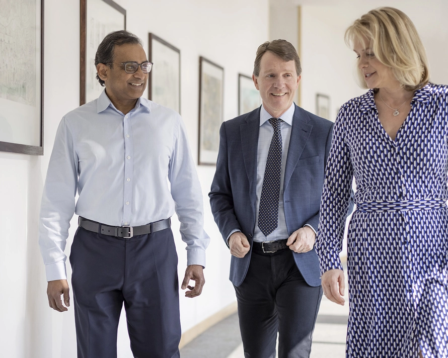 A group of three people walking together in an office hallway