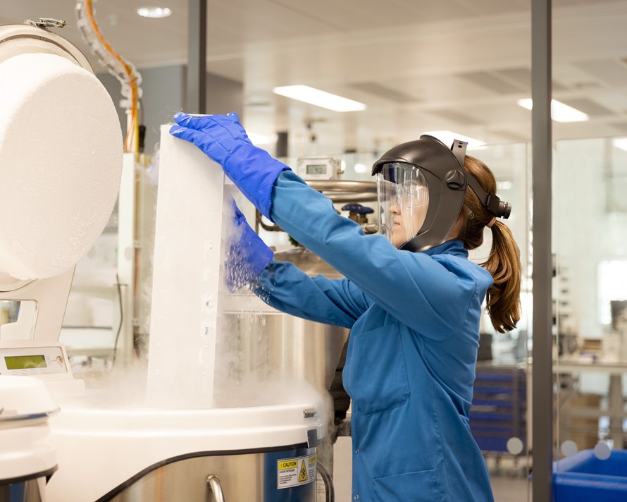 Woman opening a lab machine in protective gear
