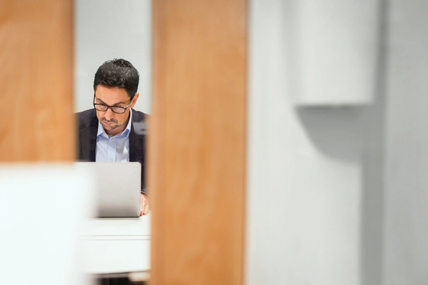 A candid view of a person working on a laptop in an office.